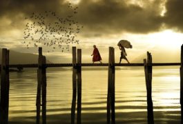 хора, които минават по мост по залез