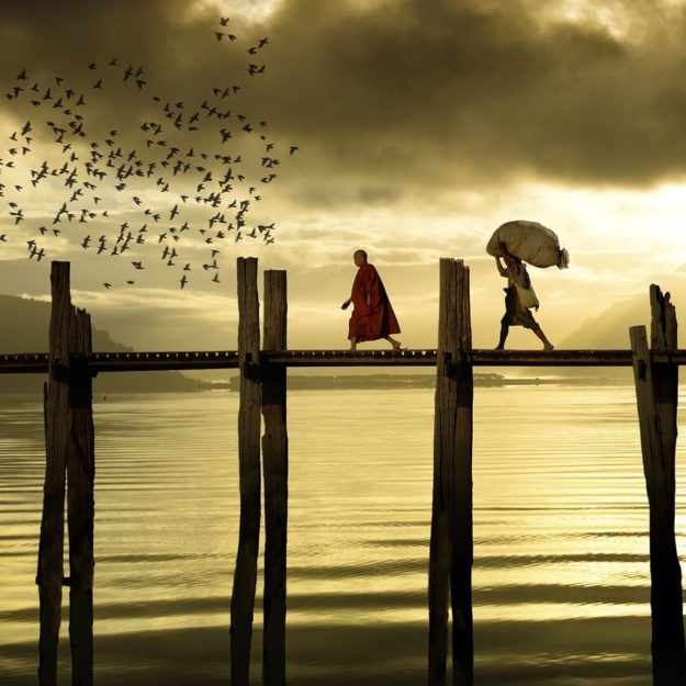 хора, които минават по мост по залез